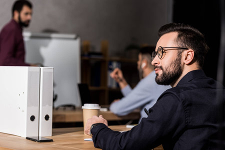 cheerful businessman sitting at meeting and looking away