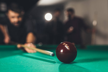 young successful handsome man playing in russian pool at bar with friends