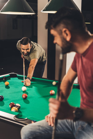 couple of young successful handsome men playing in pool at bar