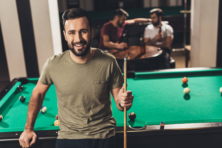 young handsome caucasian man beside billiard table in bar with friendsの写真素材