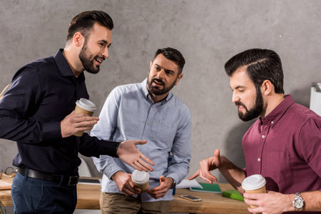 smiling businessmen talking during coffee break at office