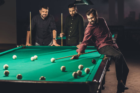 company of young successful handsome men playing in russian pool at barの写真素材