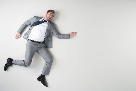 overhead view of smiling businessman in suit isolated on greyの写真素材