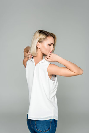 beautiful stylish woman undressing herself, isolated on greyの写真素材