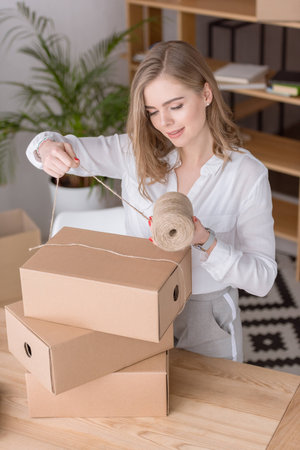 entrepreneur packing customers purchase in cardboard boxes at home officeの写真素材