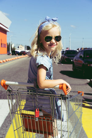 little child having fun in shopping cart at parkingの写真素材