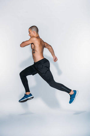 side view of african american sportsman jumping on white