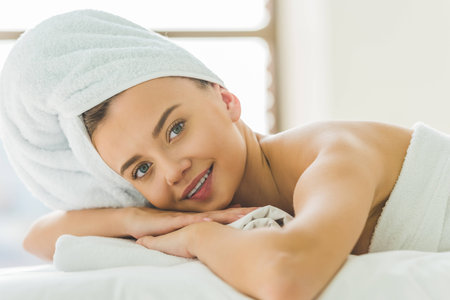 beautiful young woman relaxing on masage table at spa salonの写真素材