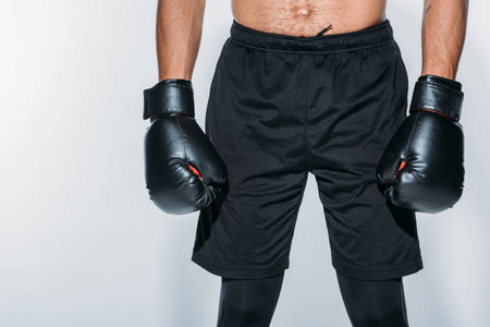 Cropped image of boxer in sport shorts and gloves isolated on whiteの写真素材