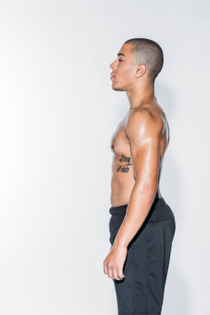 side view of tattooed african american sportsman looking away isolated on whiteの写真素材
