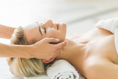 smiling young woman having facial massage at salonの写真素材