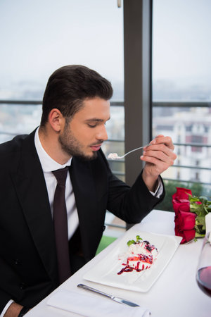 side view of man eating dessert in restaurantの写真素材