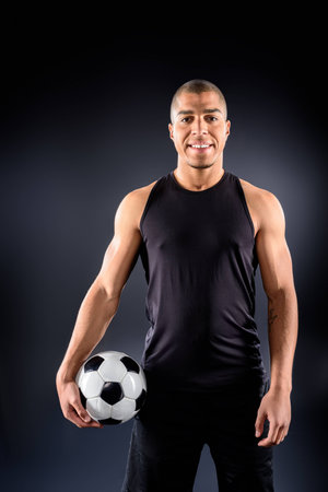 handsome african american soccer player with ball on blackの写真素材