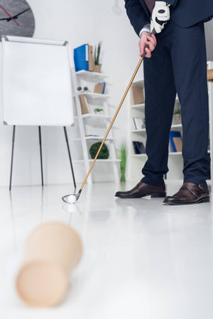 cropped shot of businessman playing golf in officeの写真素材
