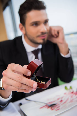 selective focus of young man presenting gift to girlfriend on romantic date in restaurant