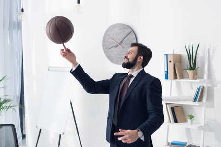 side view of young businessman in suit playing basketball in officeの写真素材