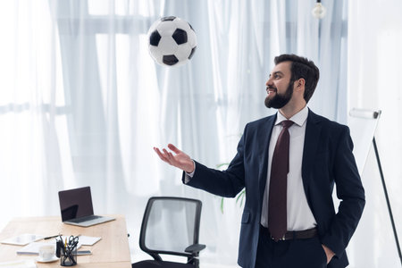 portrait of smiling businessman playing with soccer ball at workplace in officeの写真素材