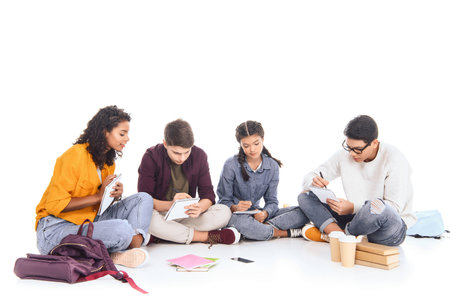 multiracial students doing homework together isolated on whiteの写真素材
