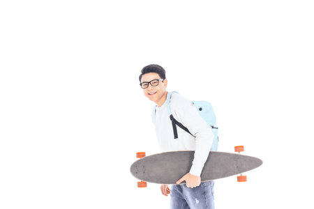 side view of asian teenager with backpack and skateboard isolated on whiteの写真素材