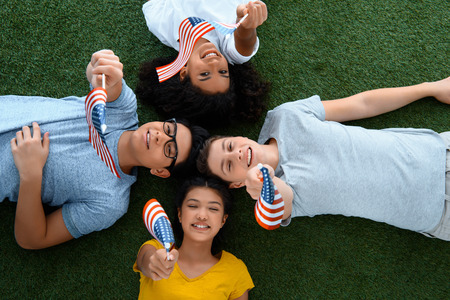 top view of group of teen students with usa flags on green grass