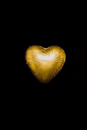 heart shaped candy in golden wrapper isolated on blackの写真素材