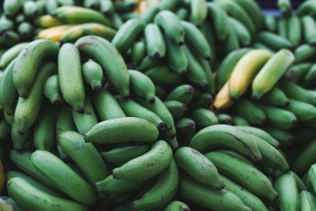 close-up shot of pile of green bananas branches selling on marketの写真素材
