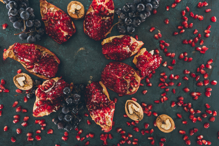Top view of pomegranate with grapes and walnuts and scattered pomegranate seedsの写真素材