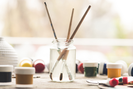 Paint brushes in a solvent and scattered containers with poster paintsの写真素材