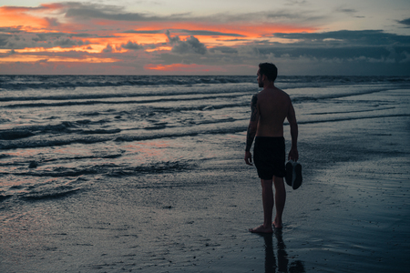 man looking at ocean at sunset in ubud, bali, indonesiaの写真素材