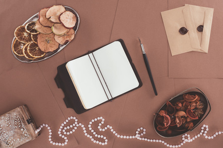 top view of notebook, jewelry box, dried fruits and envelopes over brown paper backgroundの写真素材