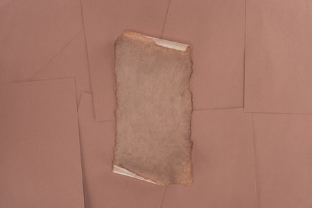 top view of old damaged paper over brown paper backgroundの写真素材