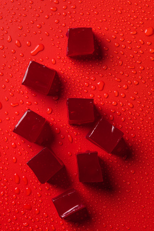 top view of candies on red surface with water dropsの写真素材
