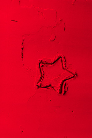 elevated view of shape of cookie cutter in shape of star on red powderの写真素材