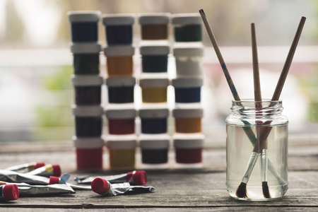 Paint brushes in a liquid and containers with poster paintsの写真素材