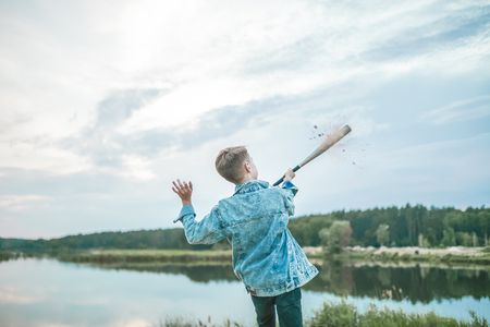 back view of boy in denim jacket playing with baseball bat outdoorsの写真素材