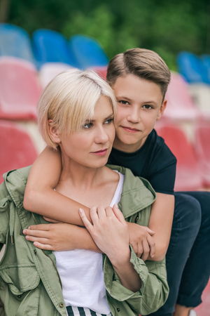 beautiful happy mother and son hugging while sitting together in stadiumの写真素材