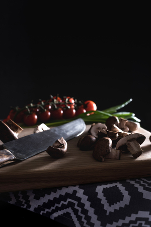 close-up shot of champignon mushrooms with knife on wooden cutting board on blackの写真素材