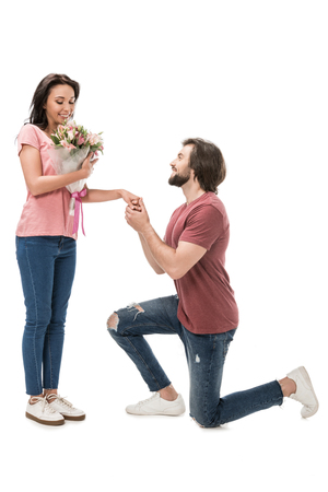 side view of woman with bouquet of flowers and man standing on one knee isolated on whiteの写真素材