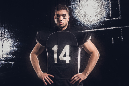 view of american football player looking at camera on black through wet glassの写真素材