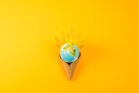 top view of earth globe in waffle cone with paper clips on yellowの写真素材