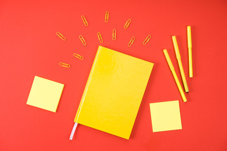 flat lay with yellow notebook with supplies on redの写真素材