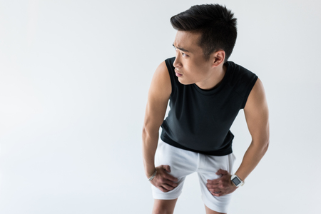 serious asian sportsman standing isolated on grey backgroundの写真素材