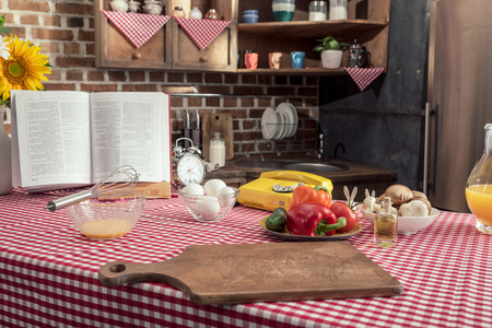 various uncooked products and recipe book on cooking table at kitchenの写真素材