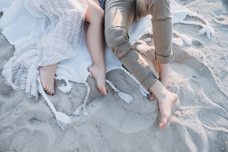 cropped top view of couple lying on blanket on beachの写真素材