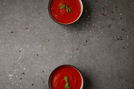 elevated view of two plates with tasty tomato soup on grey table
