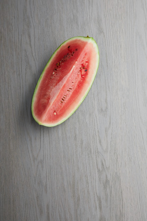 top view of fresh watermelon cut half on grey wooden tabletopの写真素材