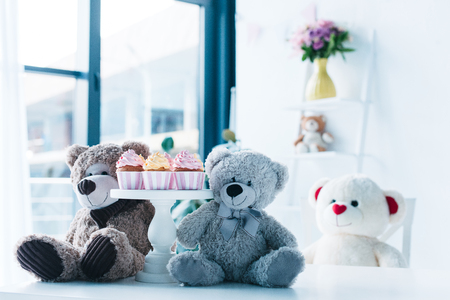 selective focus of teddy bears on table with cupcakes on standの写真素材