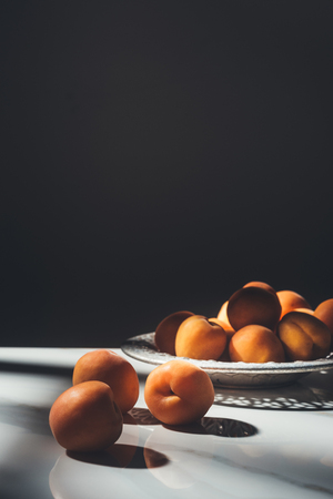 food composition with ripe apricots in metal bowl with black backgroundの写真素材