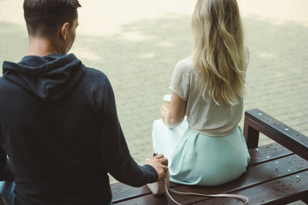back view of man pickpocketing wallet from womans bag on bench in parkの写真素材
