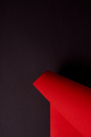 Curled red paper sheet on black backgroundの写真素材